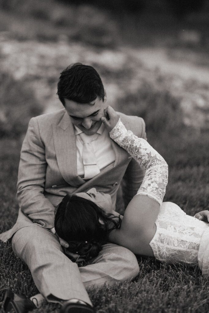 Colorado bride and groom sitting in the grass together for romantic wedding portraits